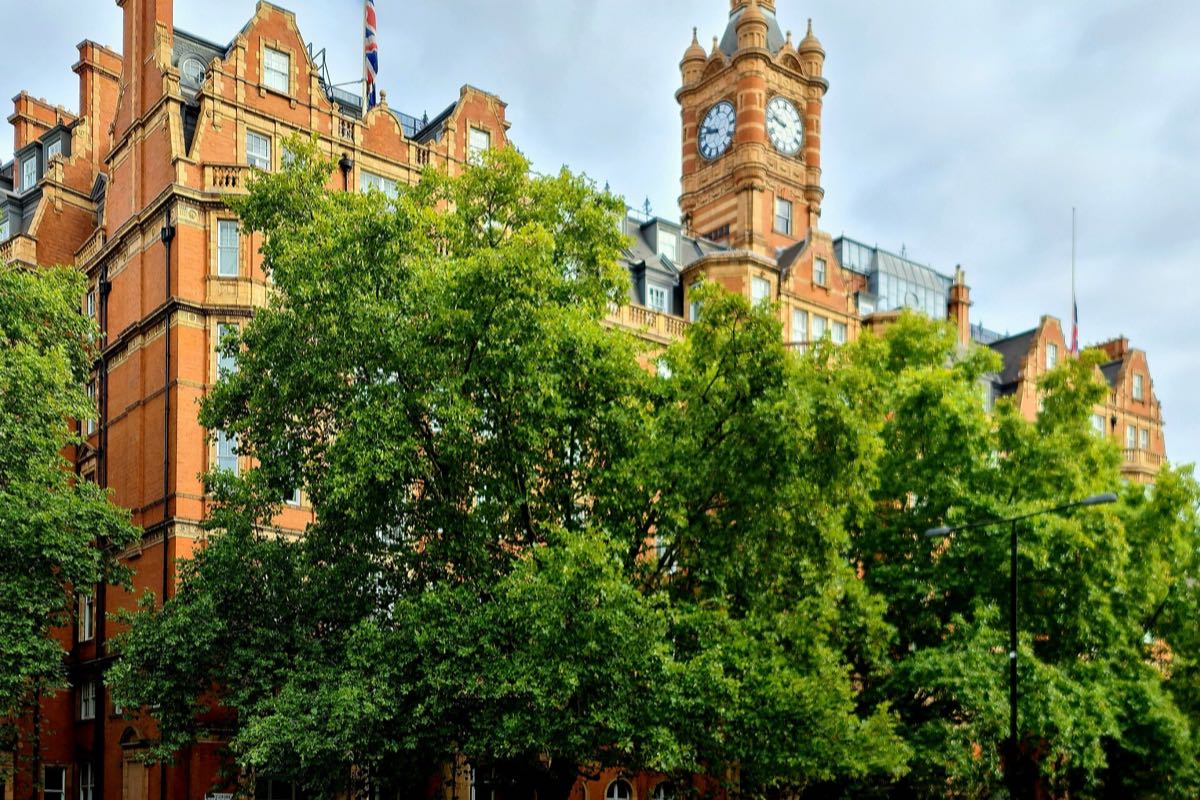 The red-brick Landmark London hotel and its clock tower on Marylebone Road, behind trees