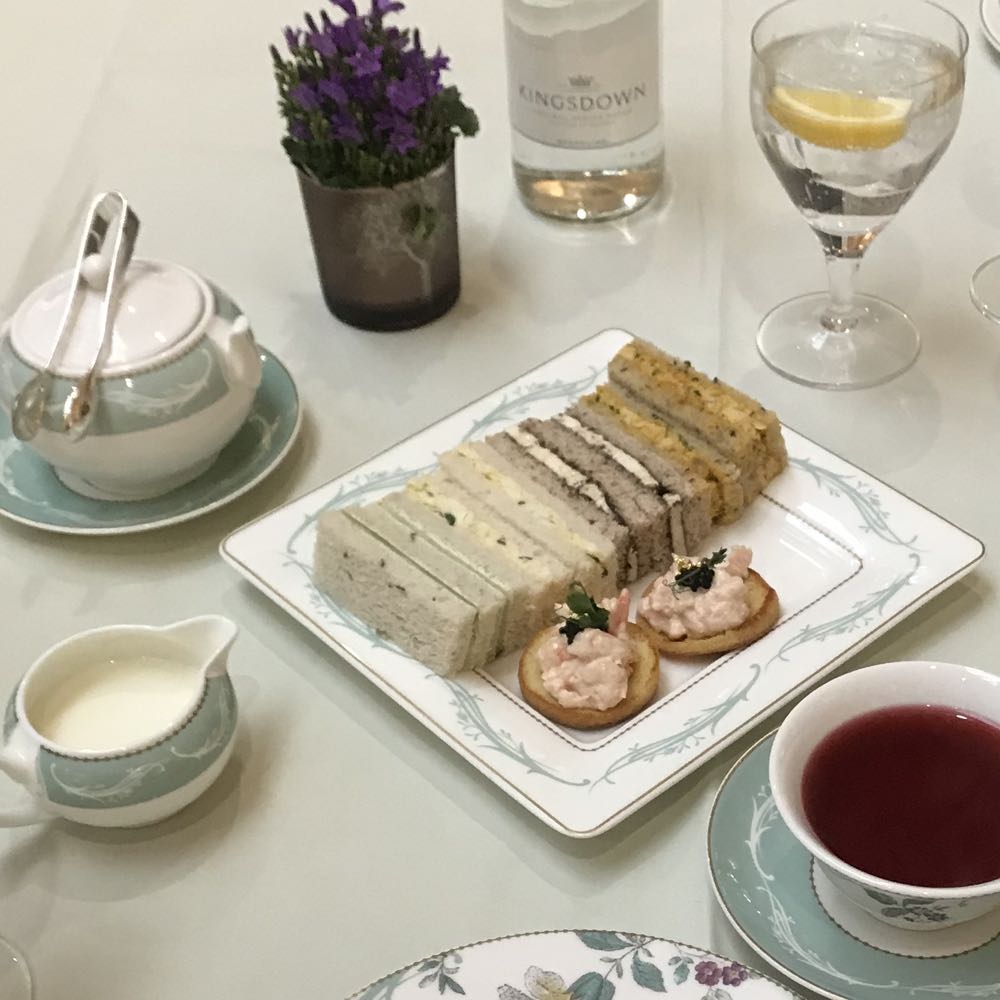 Finger sandwiches and shrimp canapés on a plate, with tea, at The Savoy's afternoon tea
